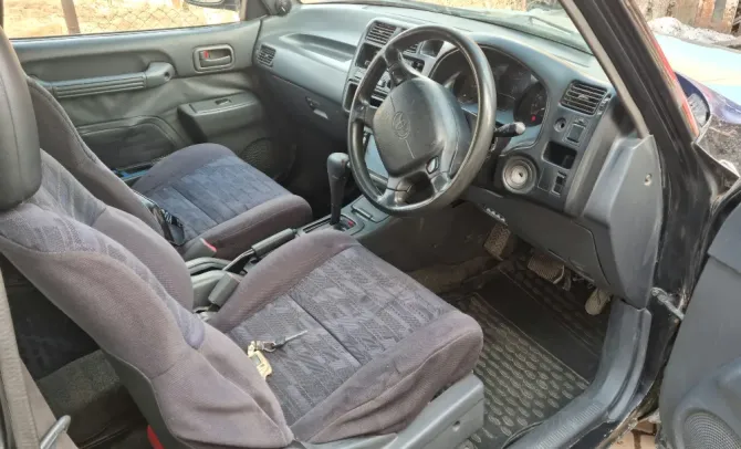 Другой ракурс передних сидений старинного внедорожника Toyota, показывающий элементы управления и современное оснащение