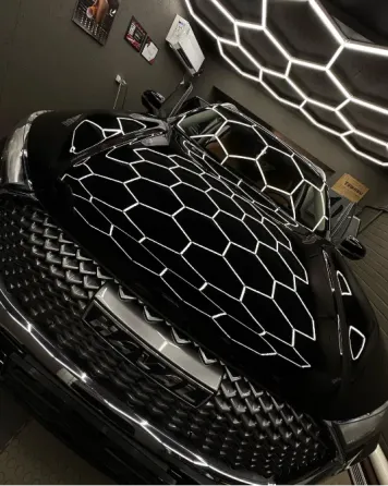 Черный автомобиль с эффектной решеткой на капоте под неоновым светом