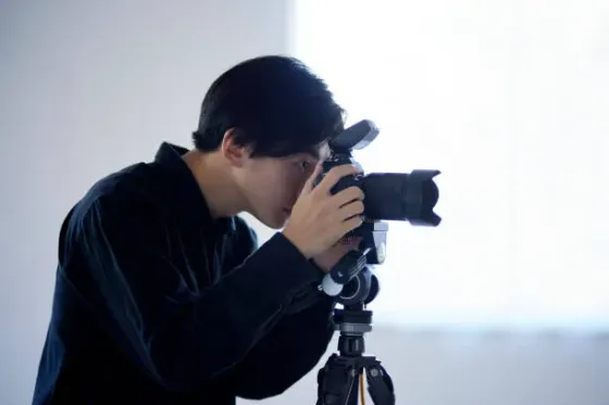 Студияда түсіру үшін камерасын баптап жатқан фотограф