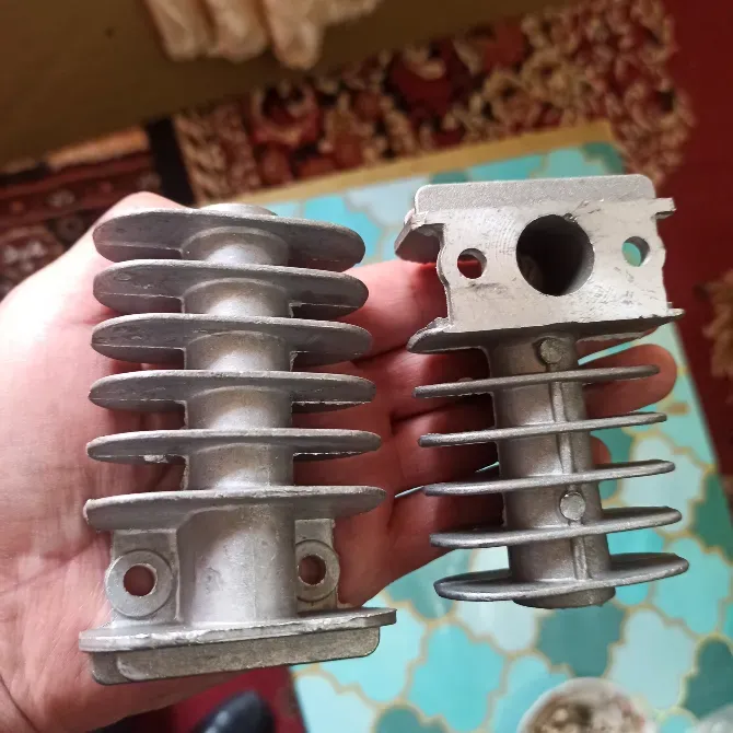 Екі алюминий бөлшегі, біреуі тесігі бар, екіншісі тесігі жоқ, адамның қолында, салқындату үшін қабырғалармен.