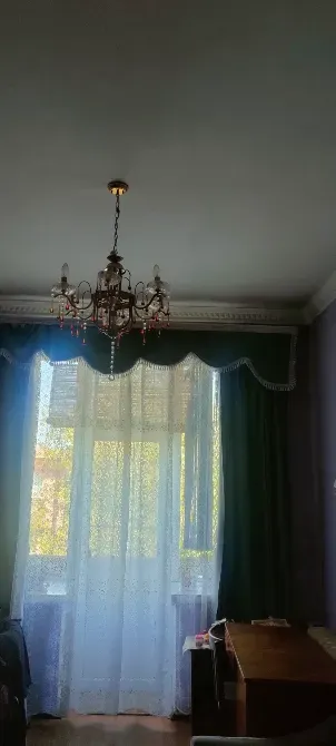 Люстра мен перделері бар бөлме интерьері