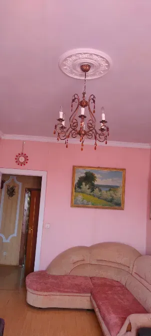 Люстра мен қабырғасында картинасы бар қонақ бөлмесі