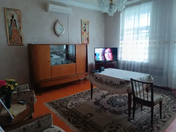Спальня с телевизором, столом и мягкой мебелью на ковре
