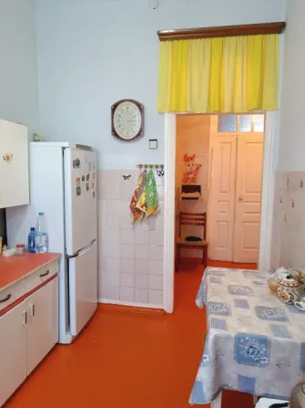 Кухня с холодильником и часами, оранжевый пол