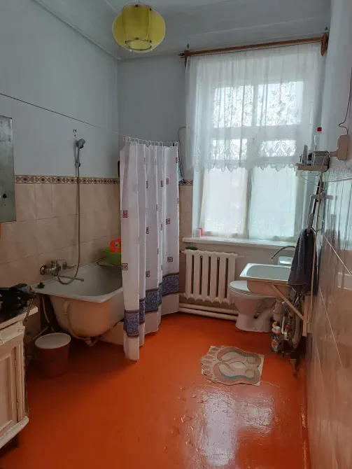 Ванная комната с ванной и раковиной на оранжевом полу