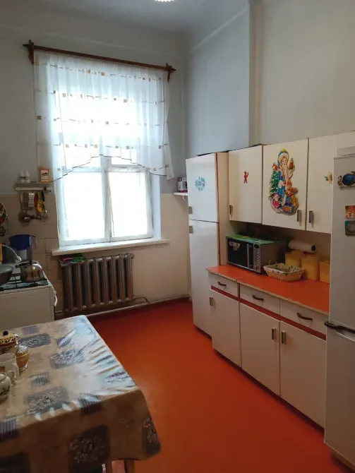 Кухня с холодильником и столом, оранжевый пол