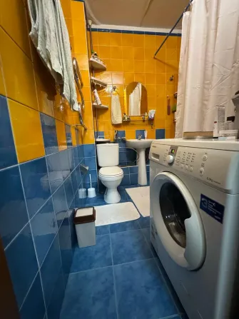 Киім жуу машинасымен және жарқын плиткамен ванна бөлмесі