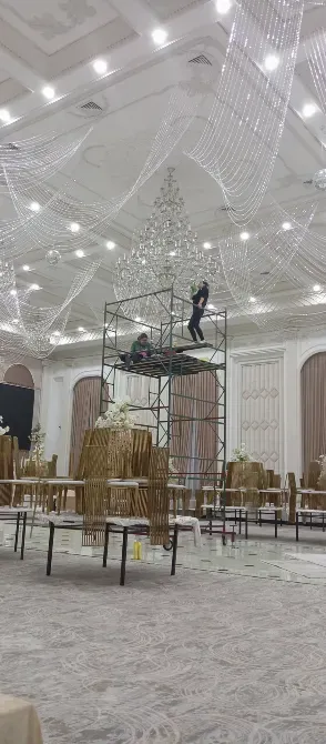 Работа по установке кристального светильника в большом зале с использованием строительных лесов