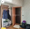 Киім ілгіштерімен прихожая, ашық есікпен және есік жанындағы әртүрлі заттармен.