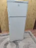 Гүлді өрнекпен безендірілген қабырға фонында Indesit холодильнигі