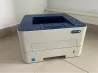 Xerox принтері, ақ және көк фоннда, плитка төсеніші үстінде орналасқан ықшам модель.