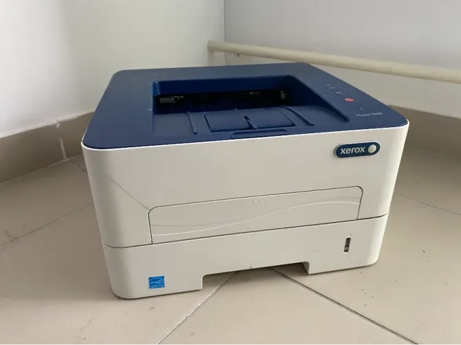 Принтер Xerox на белом и синим фоне, компактная модель, расположенная на плиточном полу