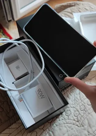 Смартфон Xiaomi 15 Ultra в руке над коробкой с аксессуарами