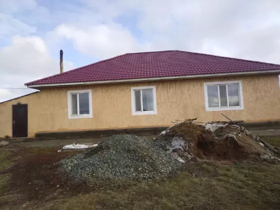 Задняя сторона дома с ведром и строительным мусором