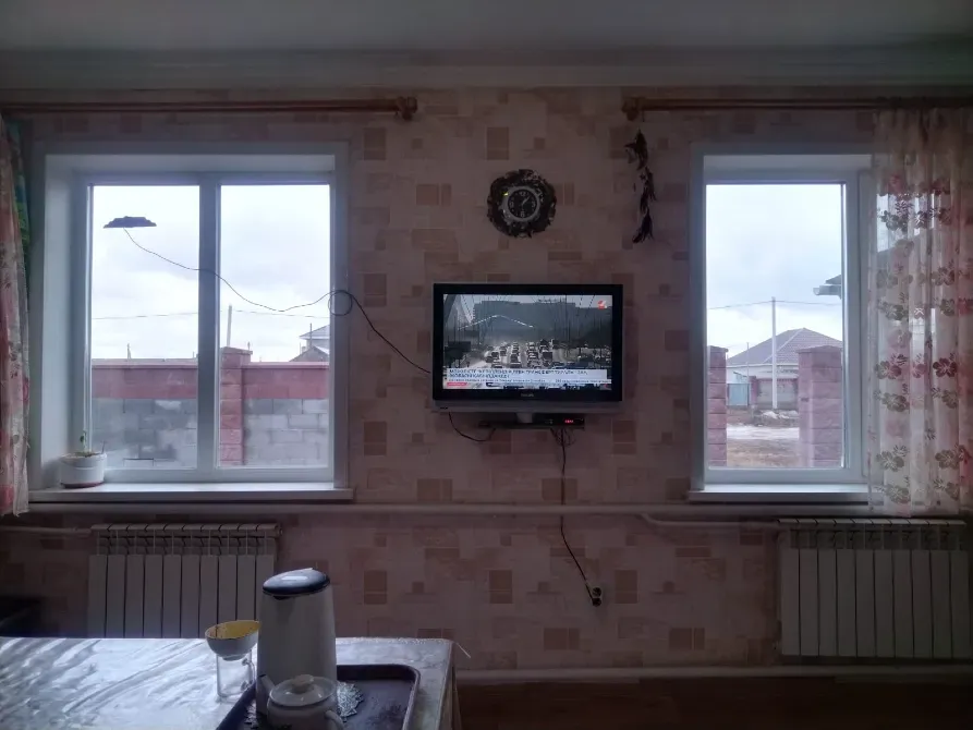 Интерьер комнаты с телевизором и двумя окнами