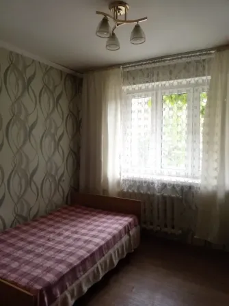 Кең жатын бөлме бір кісілік төсектен және перделермен безендірілген терезелермен