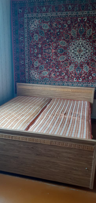 Кровать с двумя матрасами и восточным ковром на стене