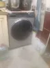 Фронтальды жүктелетін кір жуғыш машина асханада, пластик бөтелкелер мен ыдыстардың жанында.