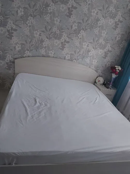 Гүлді wallpaper фонында тартылған ақ жастықшамен төсектік