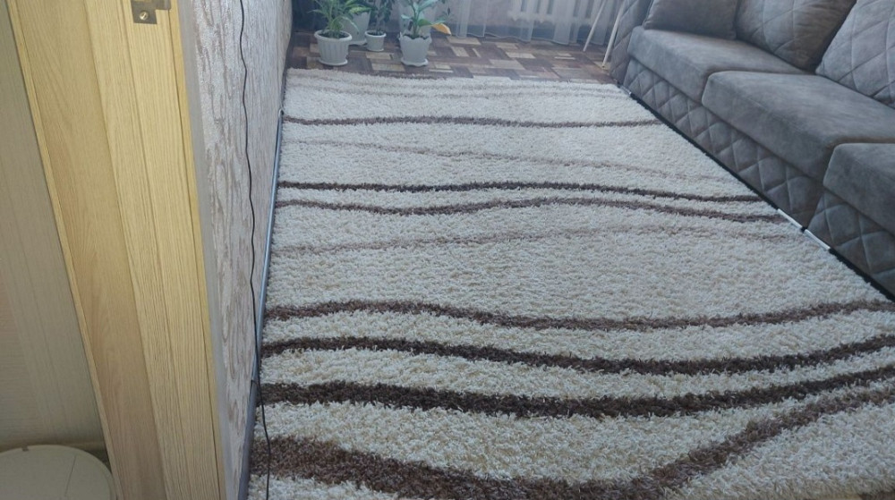 Ковровое покрытие с волнистыми линиями в комнате с серым диваном