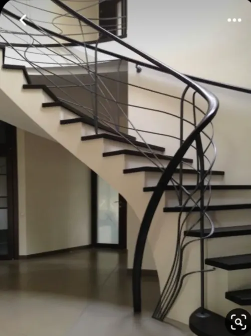 Кованая лестница с черным перилами и белой отделкой в современном интерьере
