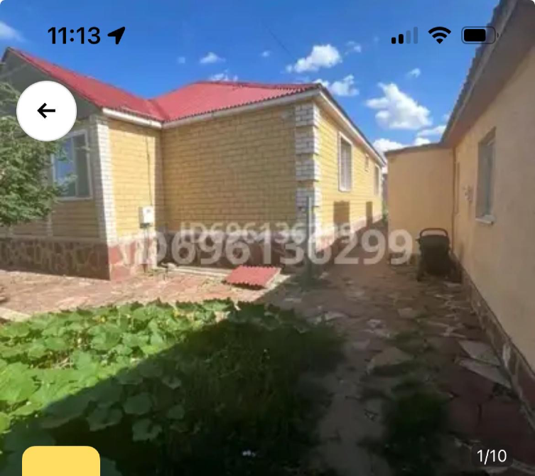 Сторона дома с зеленым двором и тротуаром из плитки