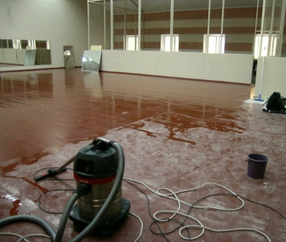 Процесс чистки пола с использованием пылесоса в спортивном зале