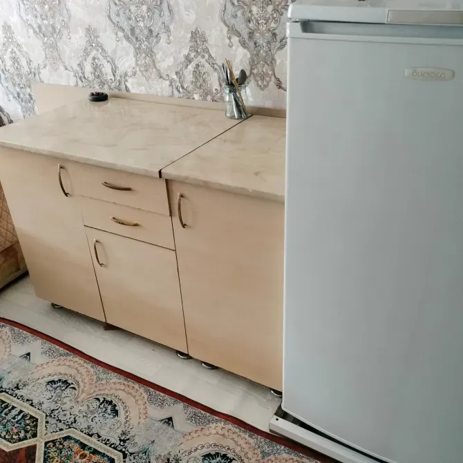Кухонный шкаф с мраморной столешницей и холодильником рядом
