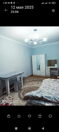 Спальня с двуспальной кроватью, светлым текстилем и современным светильником
