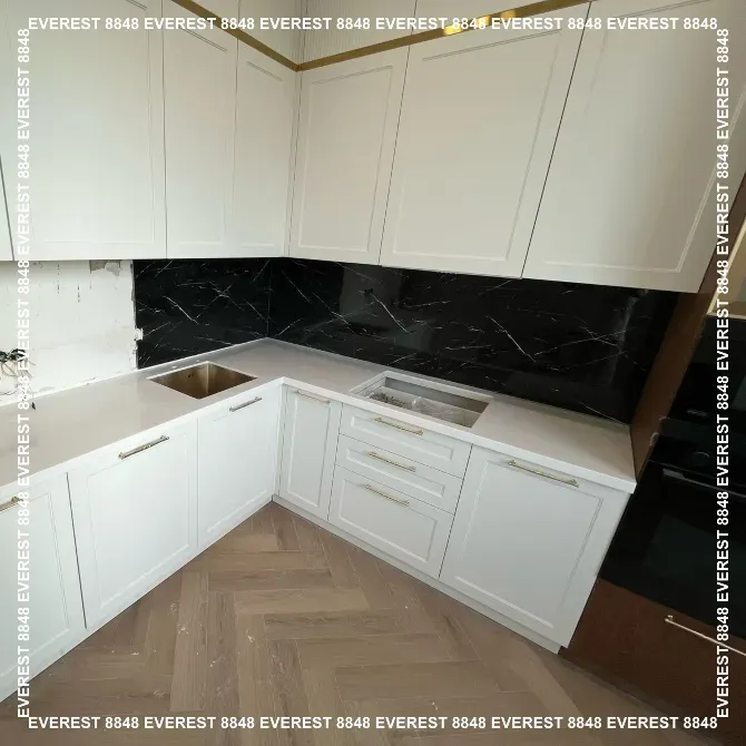 Угловая кухня с черной плиткой и белыми шкафами