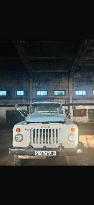 Старый грузовик с грязным кузовом и уширенной кабиной, стоящий в заброшенном здании