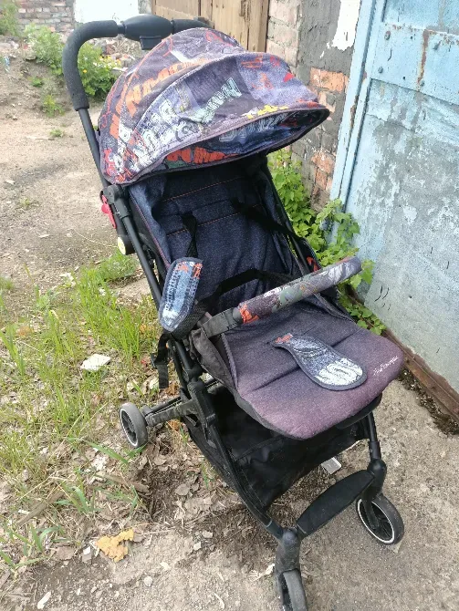 Қабырға мен өсімдіктердің фонында жиналмалы балалар коляскасы