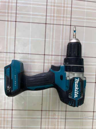 Дрель Makita с различными настройками крутящего момента на фоне клетчатого стола