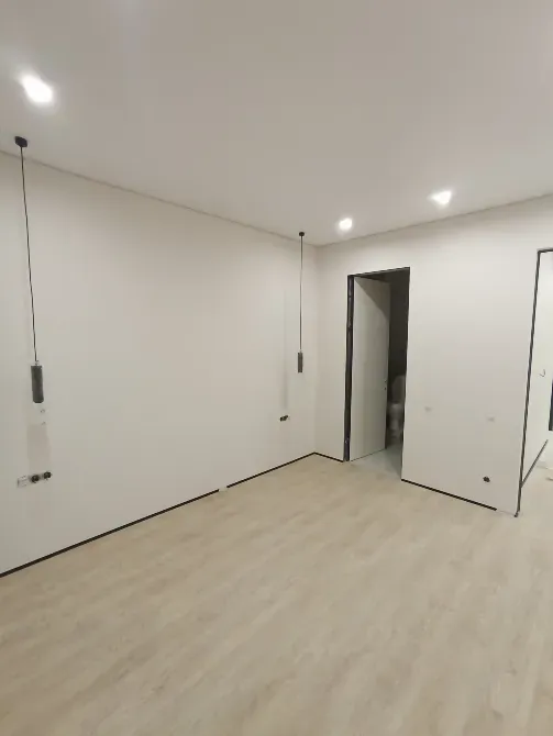 Бос бөлме ақ қабырғалармен және ағаш еденмен