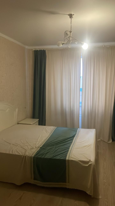 Перделері мен төбелік люстры бар екі адамдық төсектері бар жатын бөлме