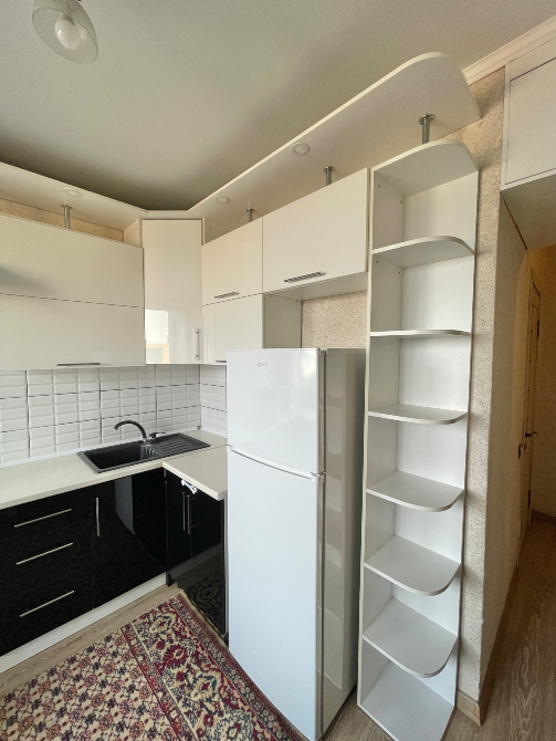 Холодильник, ақ шкафтар мен сөресі бар асхана