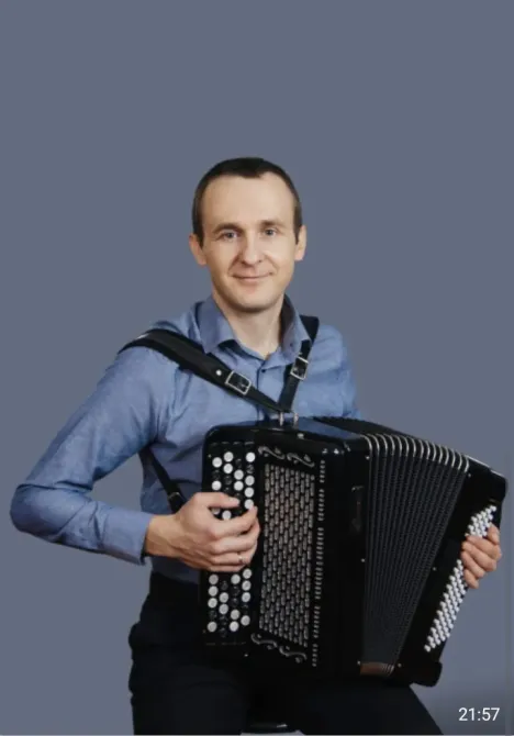 Игрок на баяне в синей рубашке с серьезным выражением лица