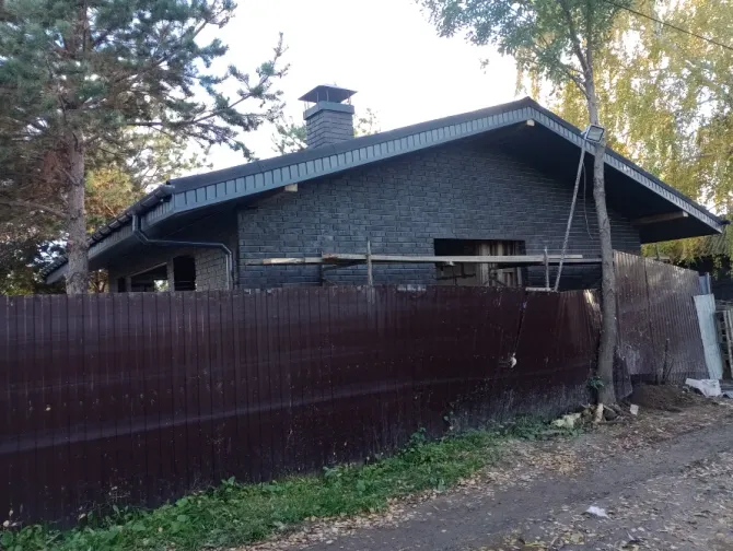 Задний двор дома с чёрной отделкой и забором