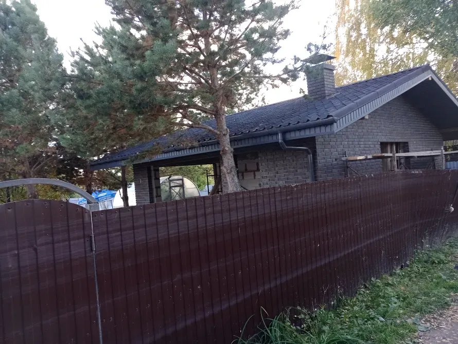 Чёрный дом с крышей и печью, окружённый забором