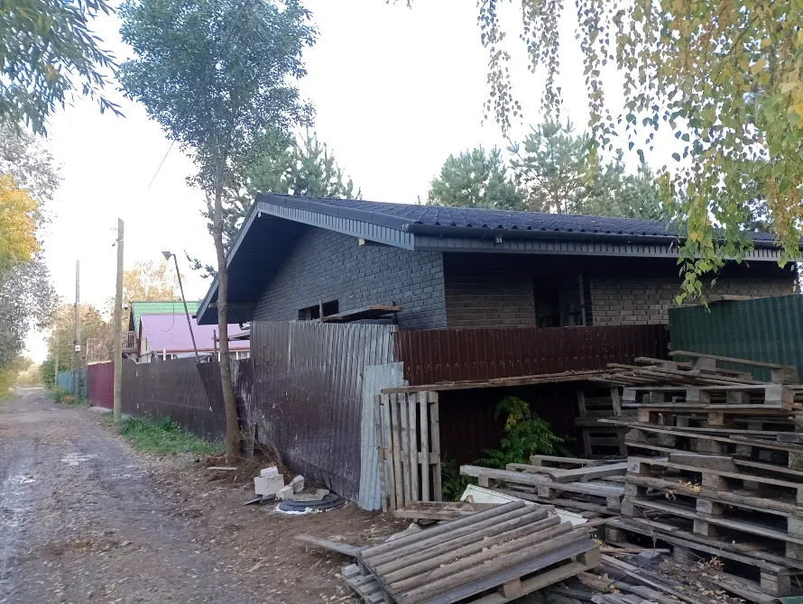 Строящийся дом с обшивкой из кирпича и открытыми окнами
