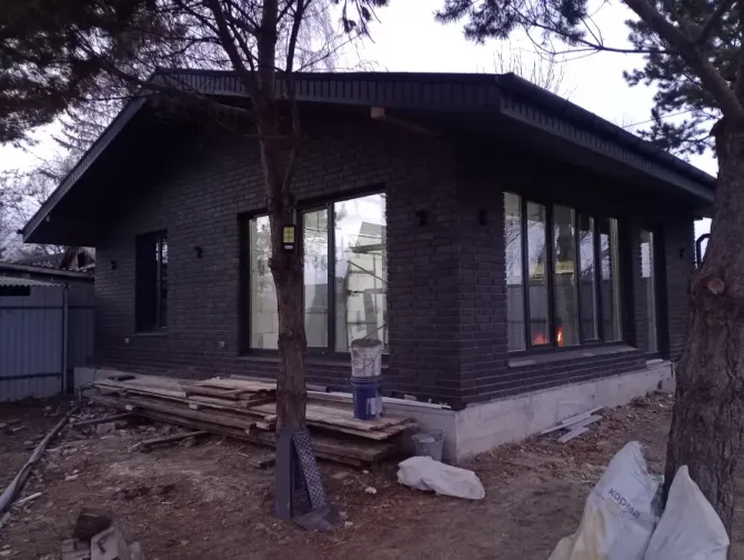 боковой вид нового дома с черной кирпичной кладкой и окнами