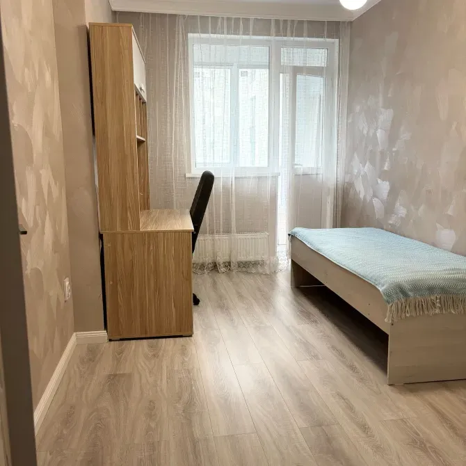 Жұмыс үстелі мен жалғыз кереуеті бар жатын бөлме
