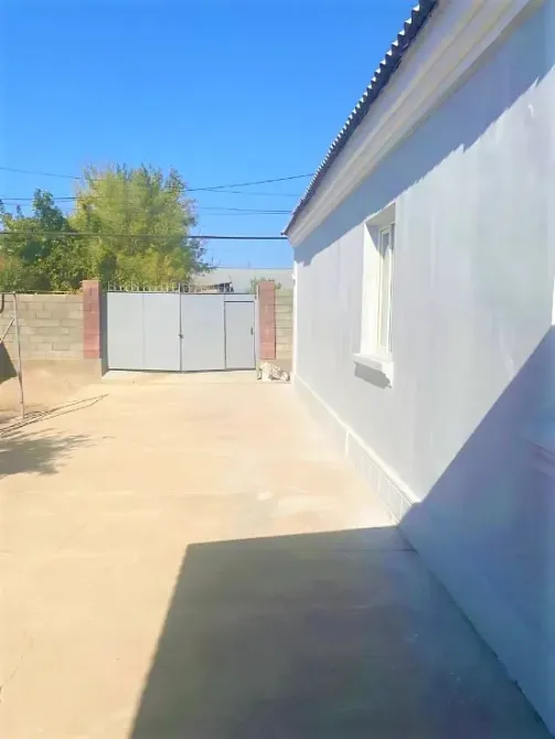 Асфальтталған алаңы мен қақпасы бар үй көк аспанның фонында