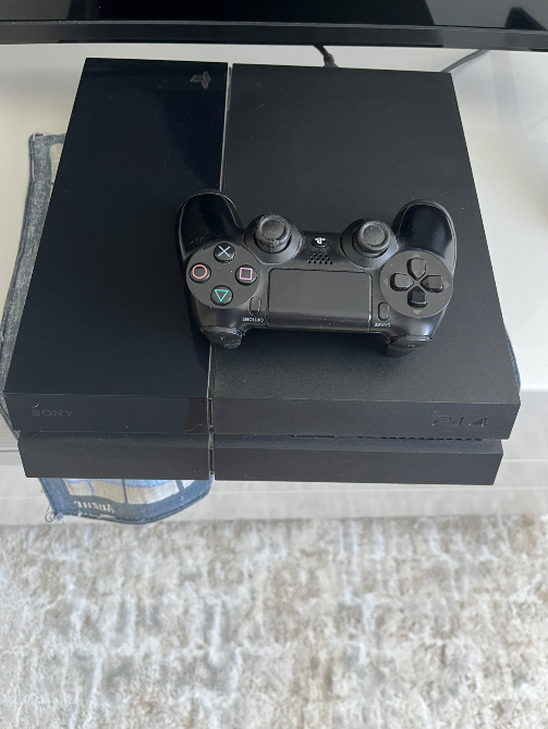 Sony PlayStation 4 ойын консолі, контроллермен бірге, үстелде.
