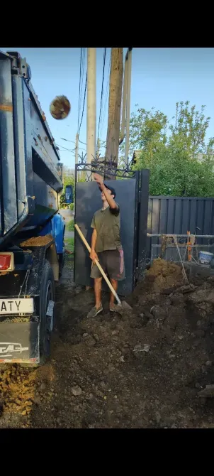 Жерді жүк көлігіне тастап жатқан жұмысшы