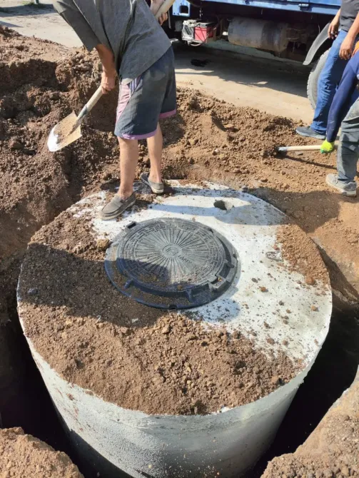 Құрылыс алаңында күрекпен жұмыс істеп жатқан адам, колодецті орнатуға дайындық