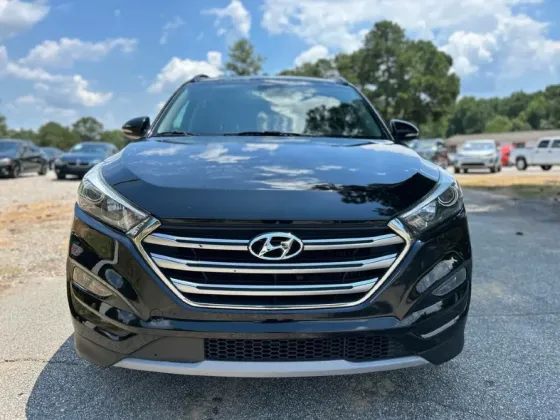 Передняя часть черного Hyundai Tucson, разглядывающая в объектив, с логотипом на решетке радиатора