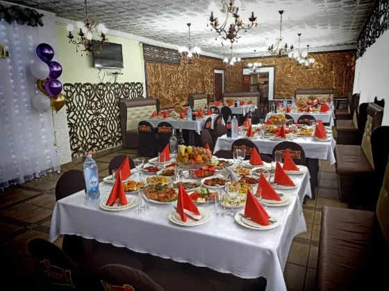 Интерьер ресторана с праздничной сервировкой стола и закусками