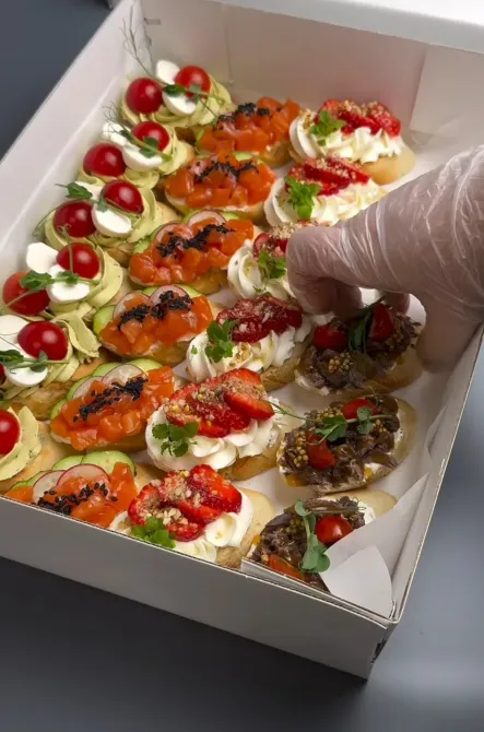 Коробка с канапе, в которой находится закуска с красной икрой и овощами