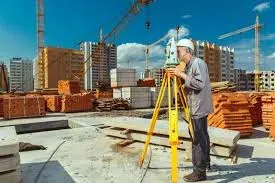 Құрылыс алаңында ғимараттың төбесінде өлшеу құралымен жұмыс істейтін геодезист
